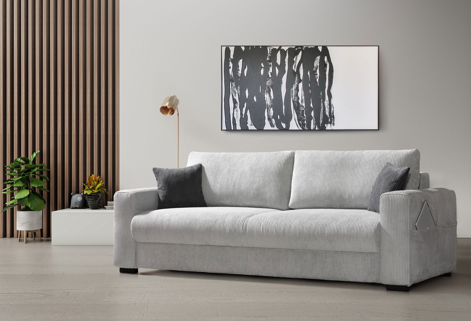 Graues Querschläfer-Sofa in einem modernen Wohnzimmer, seitliche Perspektive, mit Kissen und dekorativer Wandkunst im Hintergrund.