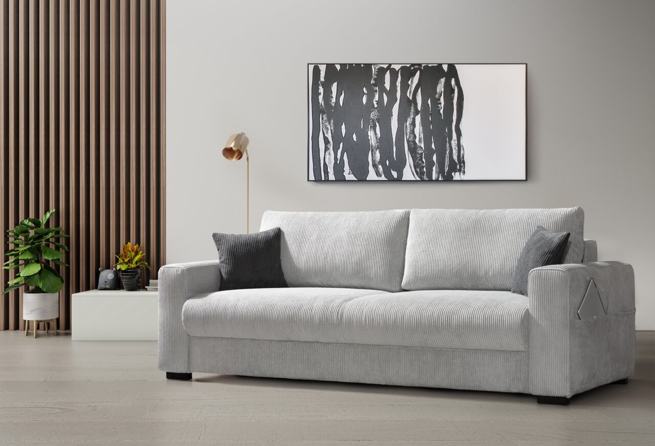 Graues Querschläfer-Sofa in einem modernen Wohnzimmer, seitliche Perspektive, mit Kissen und dekorativer Wandkunst im Hintergrund.
