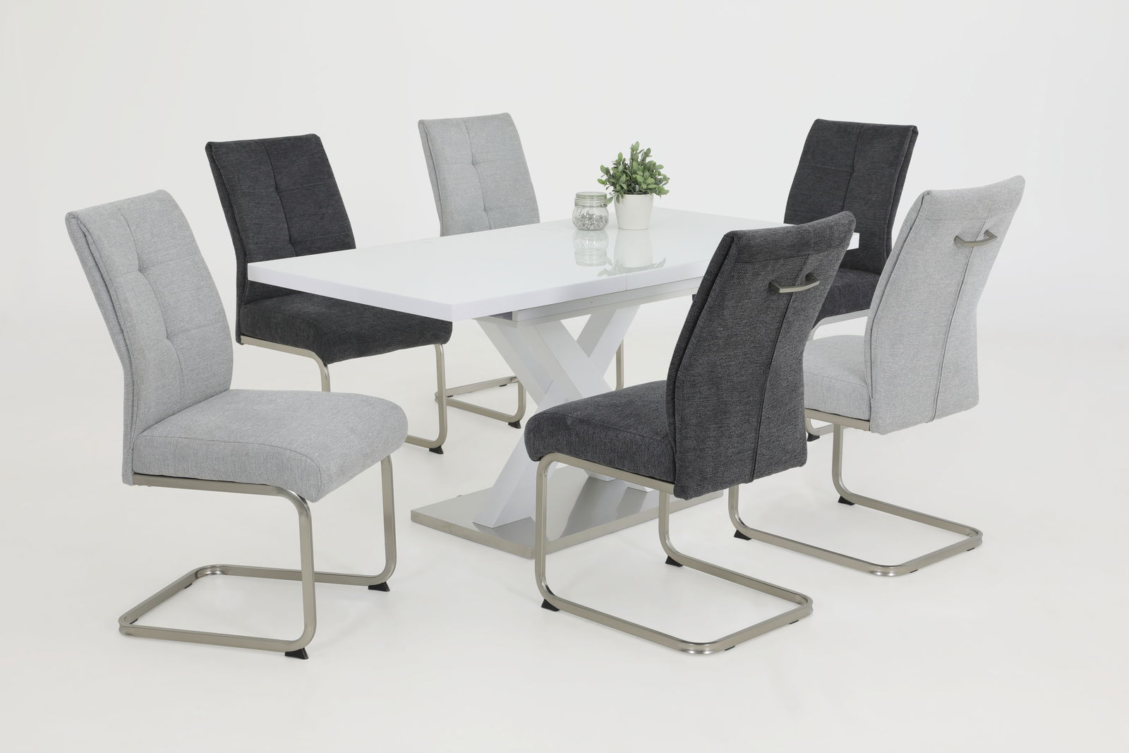 Sechs Schwingstühle in Grau und Schwarz um einen weißen Tisch, seitliche Perspektive