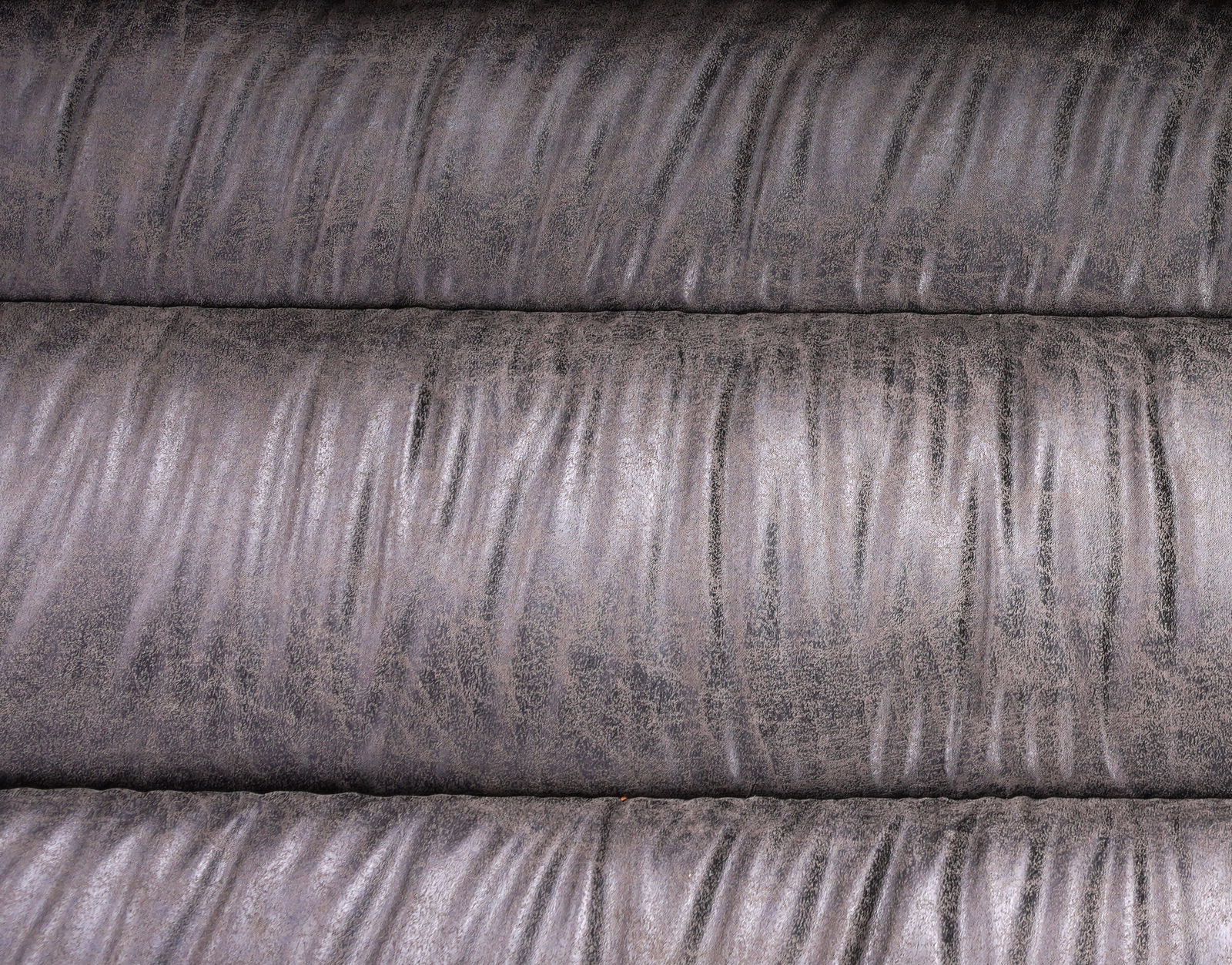 Nahaufnahme einer grauen, strukturierten Lederoberfläche einer Bank, von oben betrachtet.