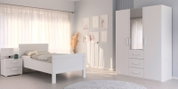 Komfortbett in einem hellen Schlafzimmer mit weißem Nachttisch und Kleiderschrank, seitliche Perspektive