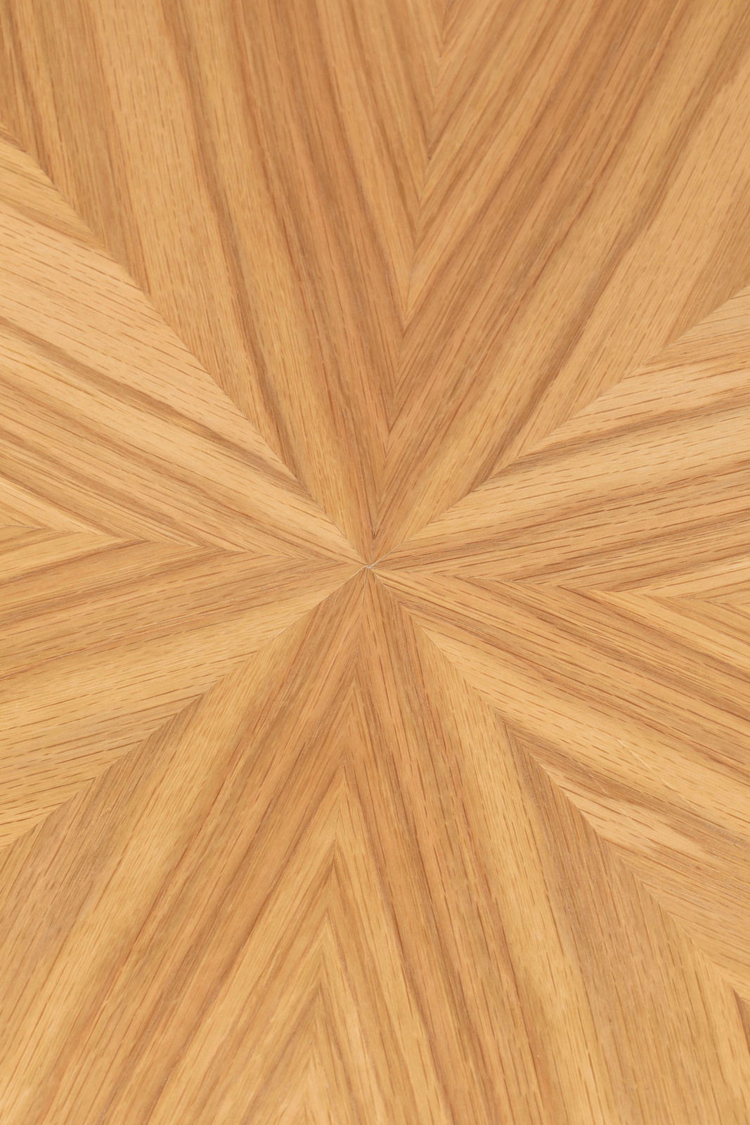 Nahaufnahme einer Tischplatte mit einem geometrischen Holzfurniermuster in warmen Brauntönen, von oben betrachtet.