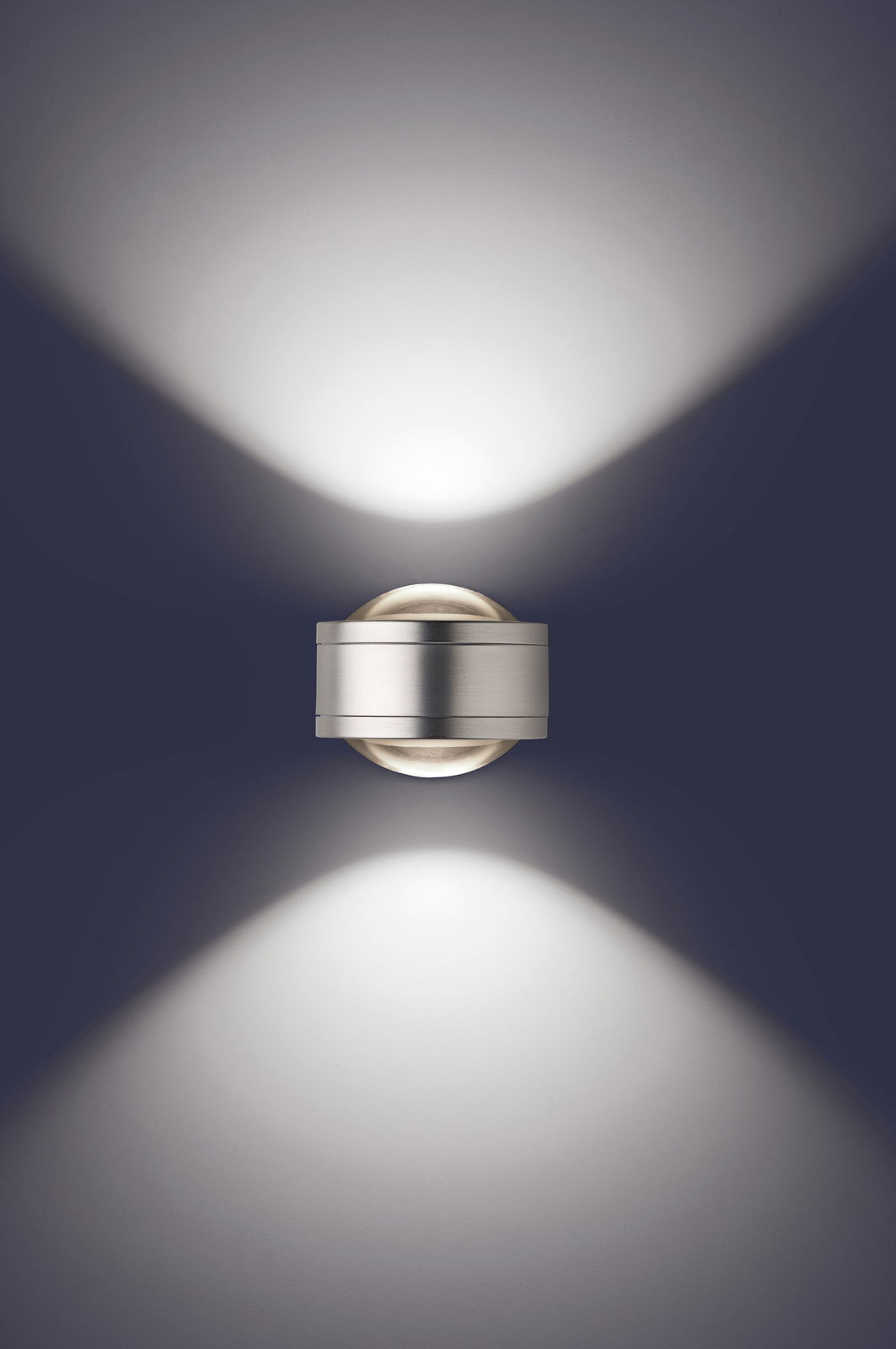 Moderne LED Wandleuchte in silberner Optik, die von oben betrachtet wird und ein elegantes Lichtmuster an die Wand projiziert.