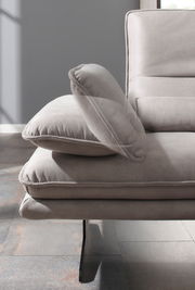 Detailansicht eines modernen Longchairs mit grauem Stoffbezug und eleganten Metallfüßen, seitliche Perspektive.