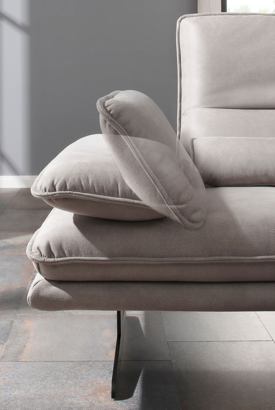 Detailansicht eines modernen Longchairs mit grauem Stoffbezug und eleganten Metallfüßen, seitliche Perspektive.