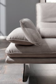 Detailansicht eines modernen Longchairs mit grauem Stoffbezug und eleganten Metallfüßen, seitliche Perspektive.