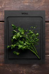 Schneidebrett S 25x19cm von oben mit frischer Petersilie darauf, auf einer Holzoberfläche.