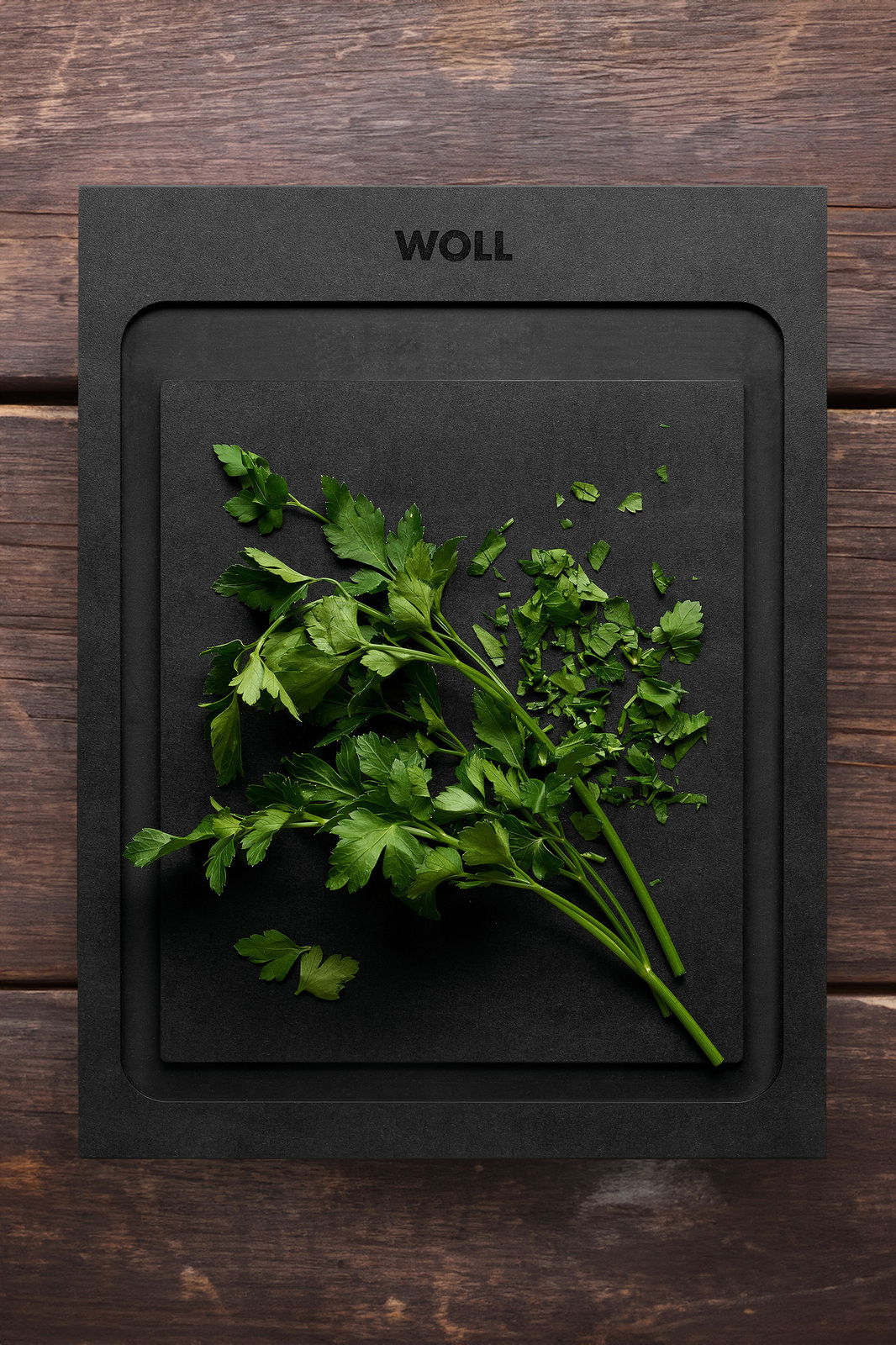 Schneidebrett S 25x19cm von oben mit frischer Petersilie darauf, auf einer Holzoberfläche.