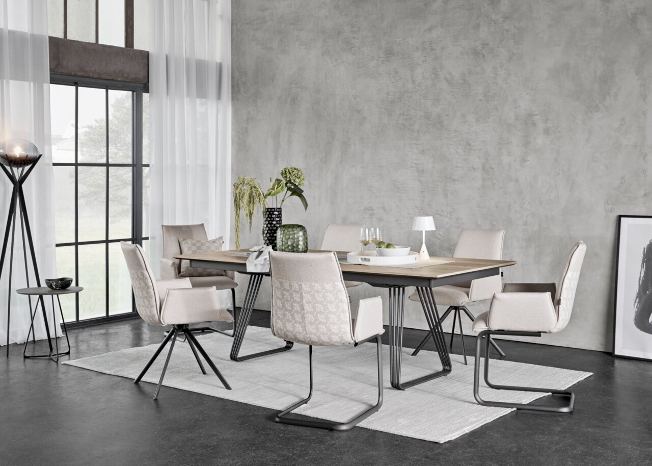 JOOP! Esstisch STUDIO G63 Modernes Esszimmer-Set mit rechteckigem Holztisch auf schwarzem Metallgestell und sechs gepolsterten Stühlen in Beige, aufgenommen in leichter Schrägansicht von vorn in einem hellen Loft-Raum.
