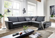 Moderne graue Leder-Eckcouch mit Ottomane und Metallfüßen im hellen Wohnzimmer, Frontansicht in leichter Schrägperspektive von links