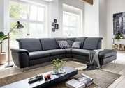 Moderne graue Leder-Eckcouch mit Ottomane und Metallfüßen im hellen Wohnzimmer, Frontansicht in leichter Schrägperspektive von links