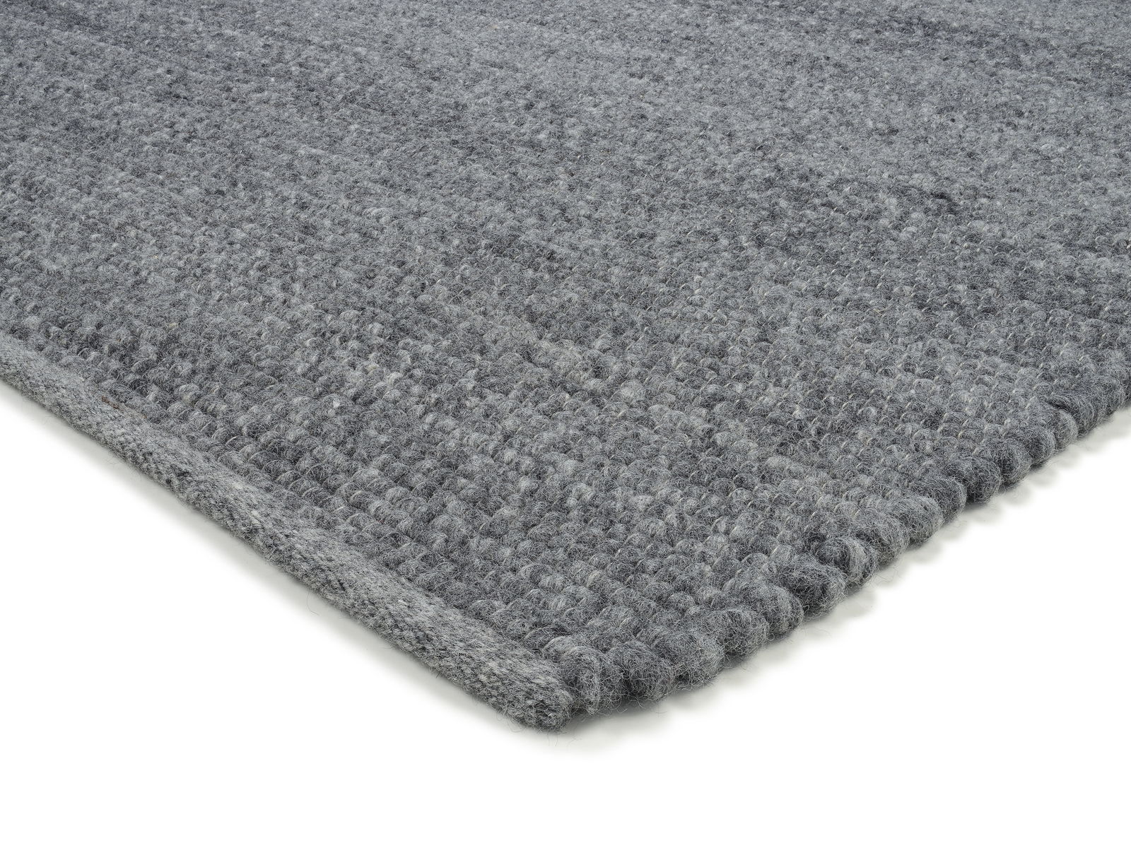 Grauer Handwebteppich in Nahaufnahme, perspektivisch von der Seite fotografiert.