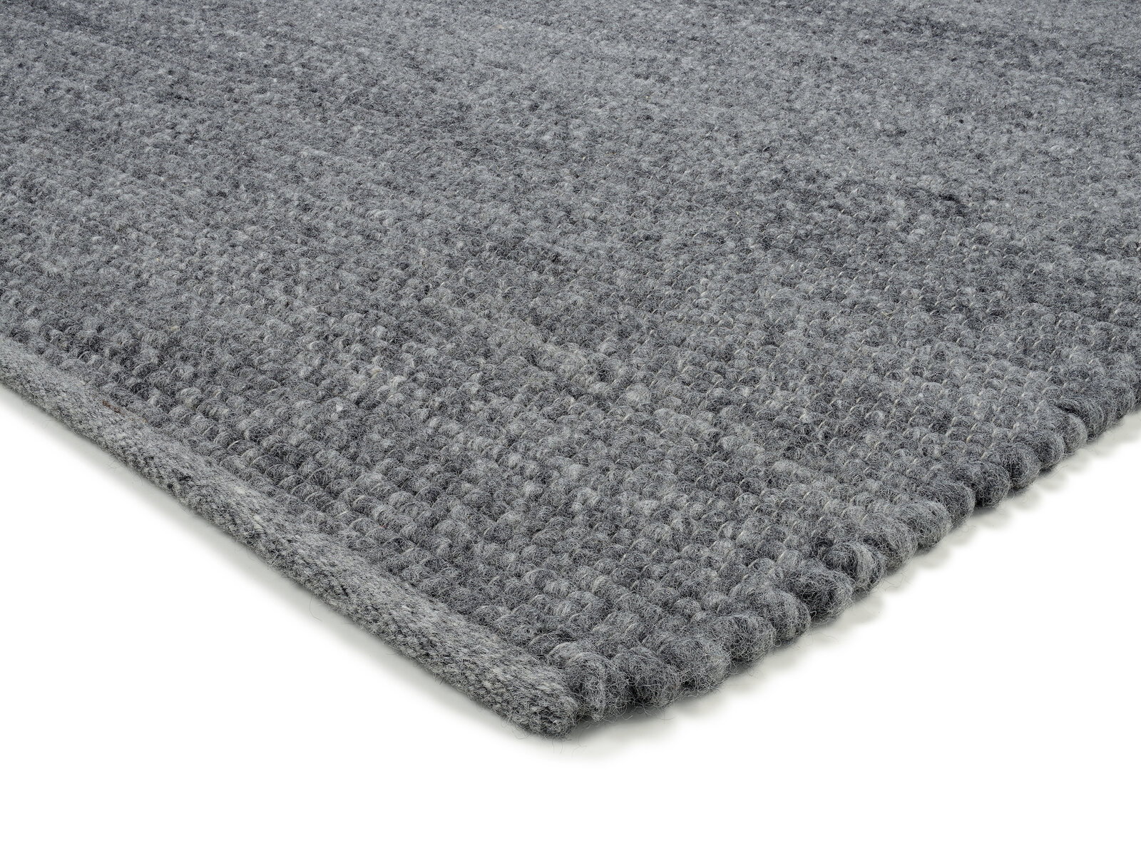 Grauer Handwebteppich in Nahaufnahme, perspektivisch von der Seite fotografiert.