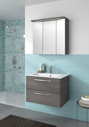 Moderner Badblock mit Spiegelschrank und Waschbecken aus der Perspektive von vorne, umgeben von blauen Fliesen.