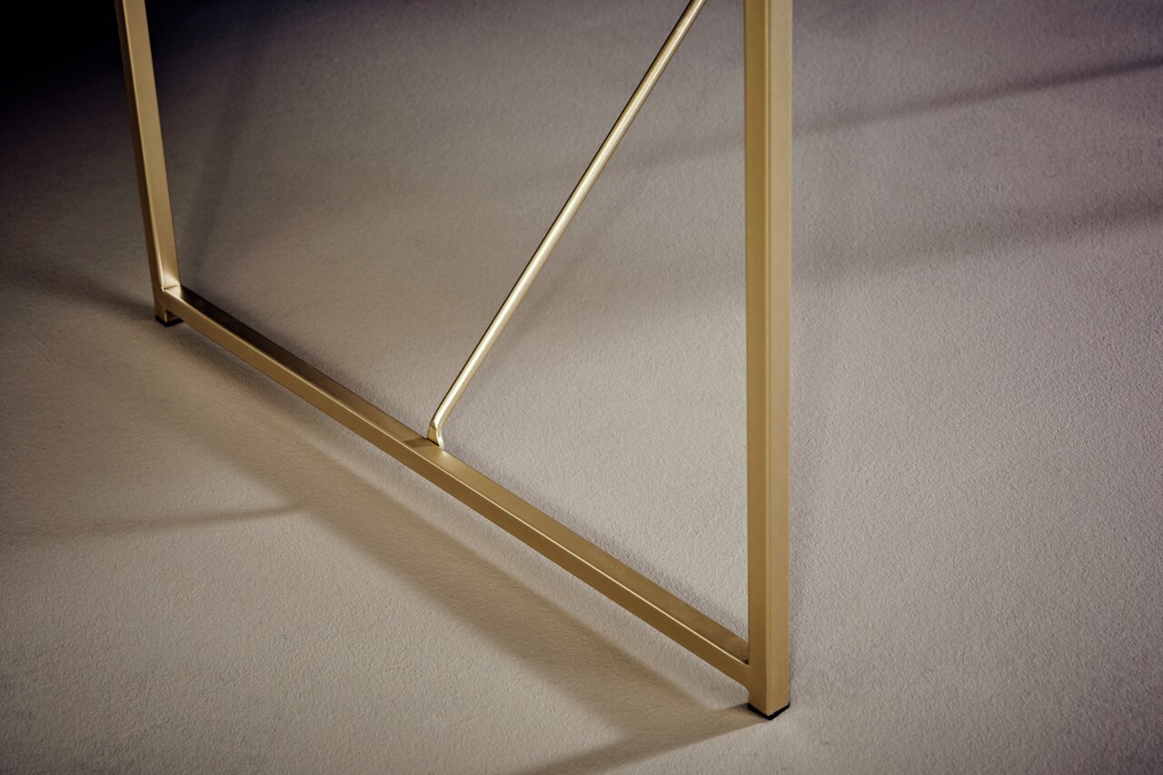 Close-up van een gouden metalen onderstel voor een consoletafel, zijaanzicht