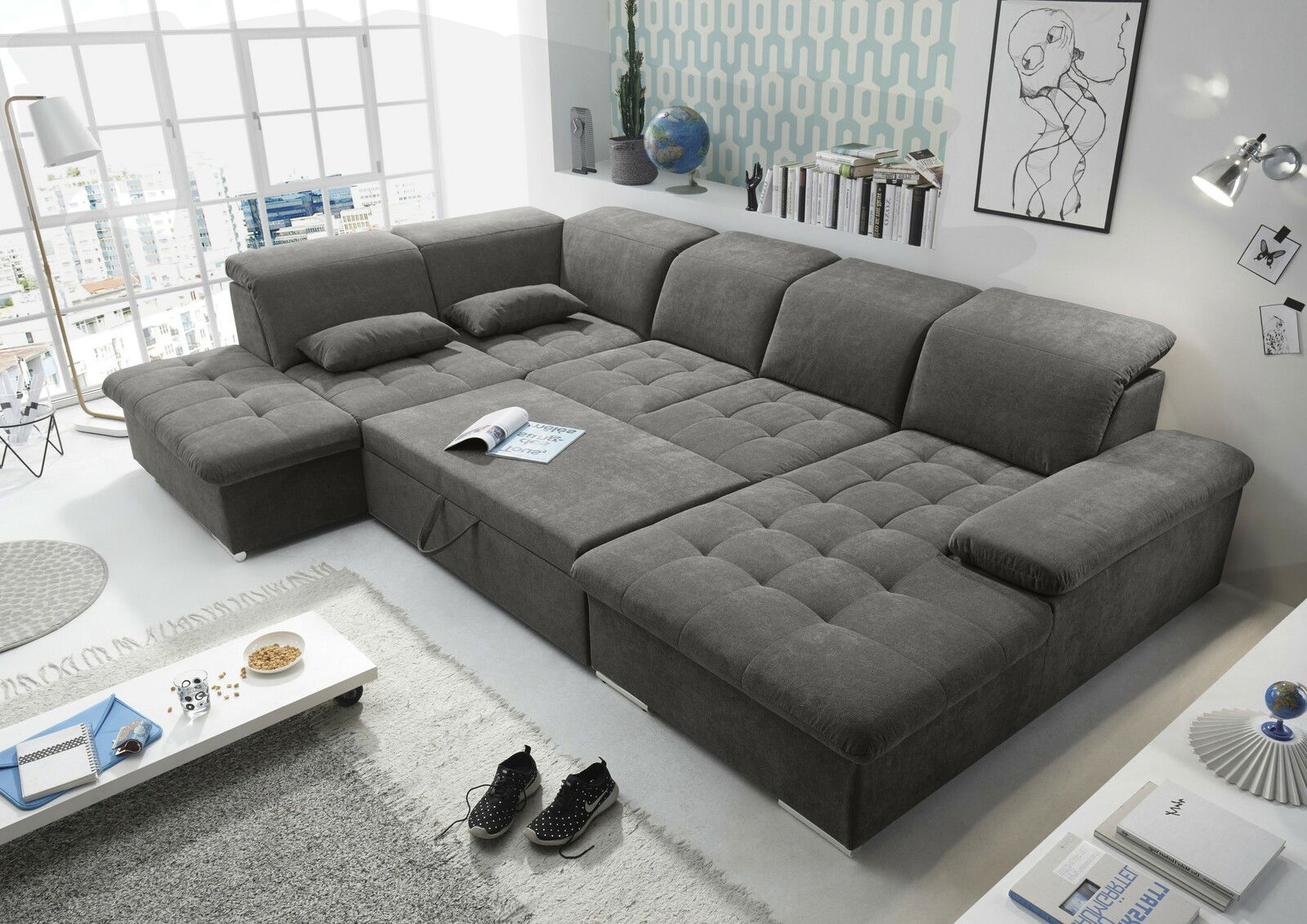Großes, graues Ecksofa in U-Form mit verstellbaren Kopfstützen und integrierter Schlaffunktion, fotografiert aus einer erhöhten Perspektive in einem modernen Wohnzimmer.