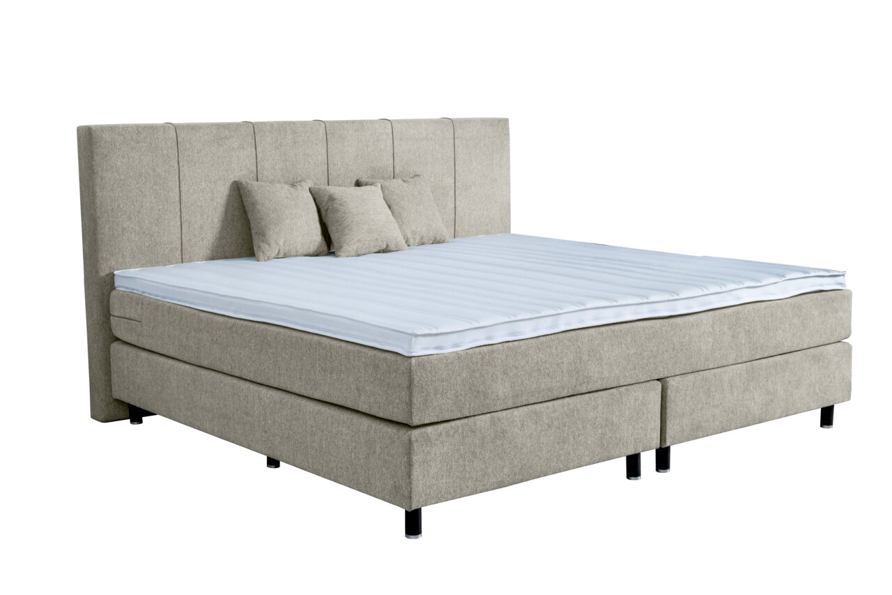 Boxspringbett in hellgrauem Stoff mit hohem Kopfteil und drei Kissen, seitliche Perspektive