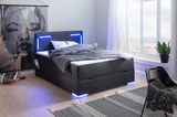 Modernes Boxspringbett mit blauer LED-Beleuchtung, seitliche Perspektive, in einem stilvoll eingerichteten Raum mit großem Fenster.