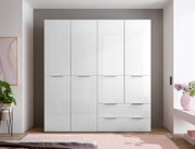 Weißer, hochglänzender Kleiderschrank mit vier Türen und zwei Schubladen, frontal aus der Vorderansicht im Schlafzimmer fotografiert