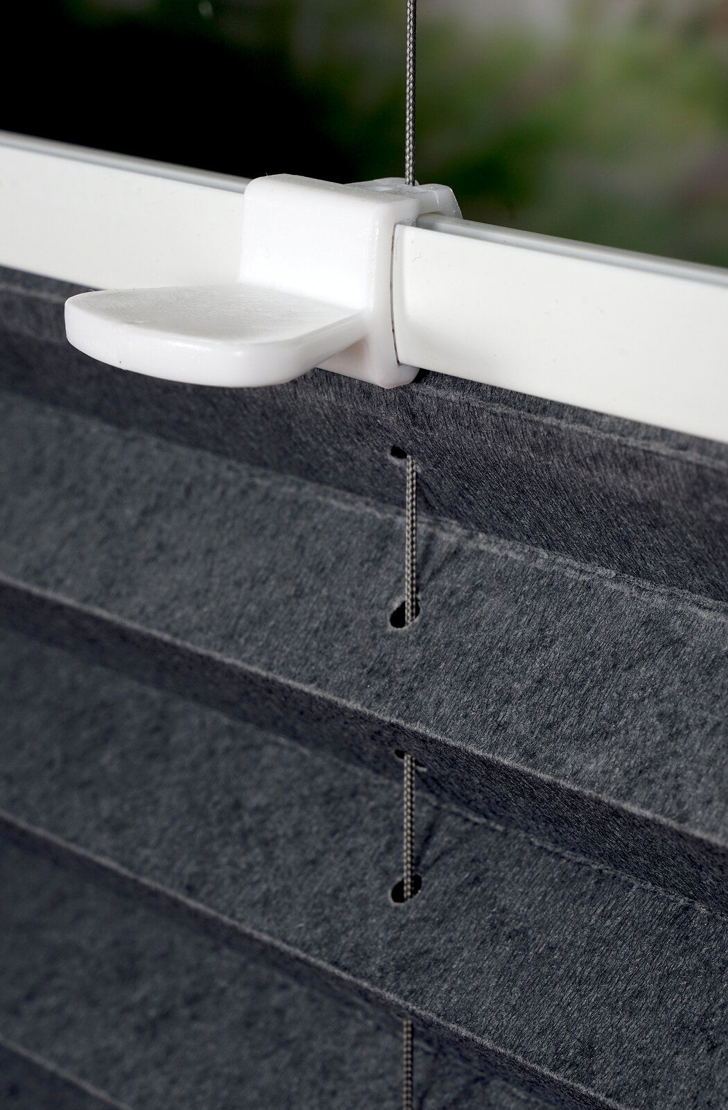 Nahaufnahme eines gefädelten Plissees in Anthrazit mit weißem Halter, seitliche Perspektive