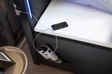 Nahaufnahme eines Boxspringbetts mit integrierter LED-Beleuchtung, USB-Ladeanschluss und seitlicher Aufbewahrungstasche, aus der eine Zeitschrift ragt. Perspektive von oben.