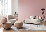 Moderne Wohnzimmermöbel mit einem Sessel, einem Hocker und einem Sofa in einem hellen Raum mit großen Fenstern, aus seitlicher Perspektive.