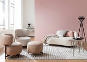 Moderne Wohnzimmermöbel mit einem Sessel, einem Hocker und einem Sofa in einem hellen Raum mit großen Fenstern, aus seitlicher Perspektive.