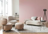 Moderne Wohnzimmermöbel mit einem Sessel, einem Hocker und einem Sofa in einem hellen Raum mit großen Fenstern, aus seitlicher Perspektive.