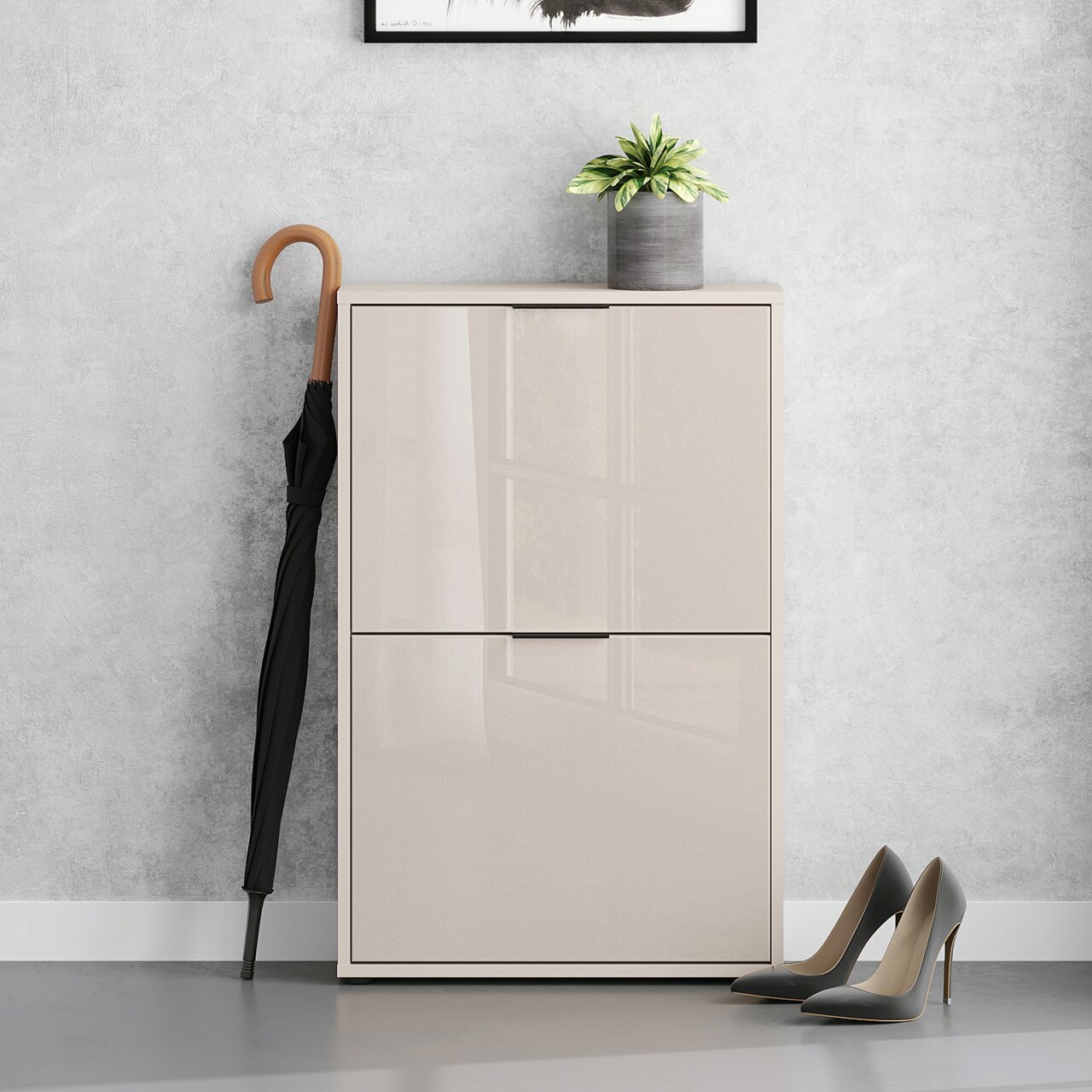 Moderne, hoogglanzende schoenenkast/dressoir in beige met twee klapdeuren, van voren gefotografeerd op ooghoogte; ernaast een zwarte paraplu, bovenop een bloempot, rechts een paar hoge hakken voor een grijze muur.