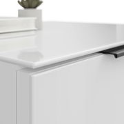 Nahaufnahme einer weißen Nachtkommode mit glatter Oberfläche und schwarzem Griff, von oben fotografiert.