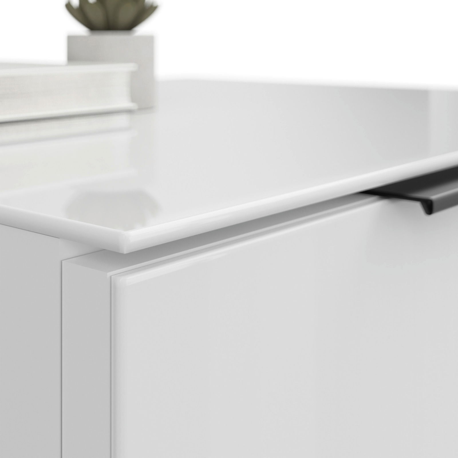 Nahaufnahme einer weißen Nachtkommode mit glatter Oberfläche und schwarzem Griff, von oben fotografiert.