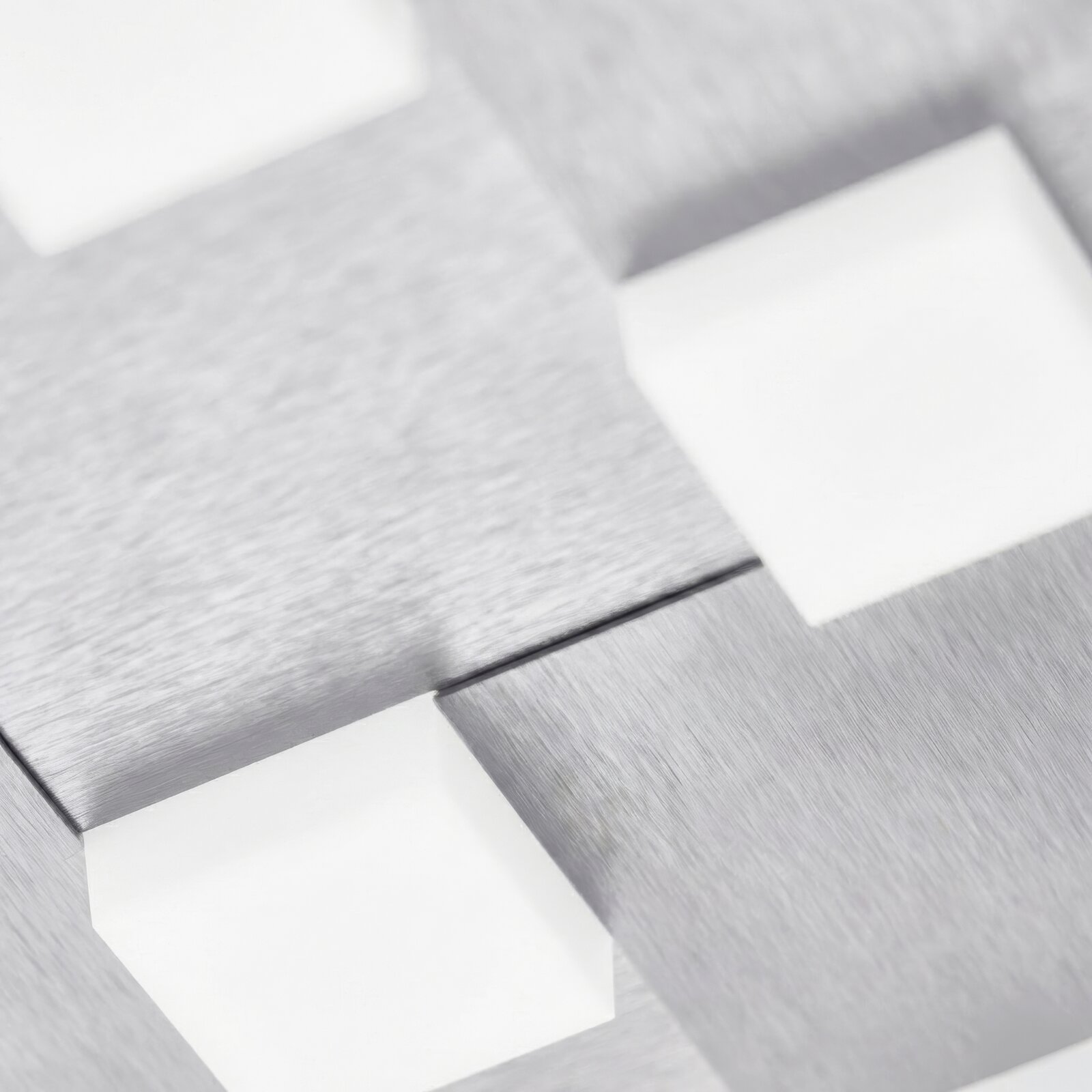 Detailaufnahme aus schräger Draufsicht auf eine moderne Leuchte mit geometrisch angeordneten Lichtflächen und gebürsteten Metallelementen in Silber