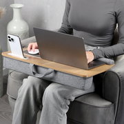 Houten laptopkussen met grijze stoffen onderkant en draaggreep, met laptop en smartphonehouder in gebruik op schoot; gefotografeerd schuin van voren op zithoogte.
