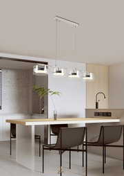 Moderne LED-Hängeleuchte mit vier runden Leuchten, aufgehängt über einem Esstisch in einer stilvollen, minimalistischen Küche. Seitliche Perspektive.