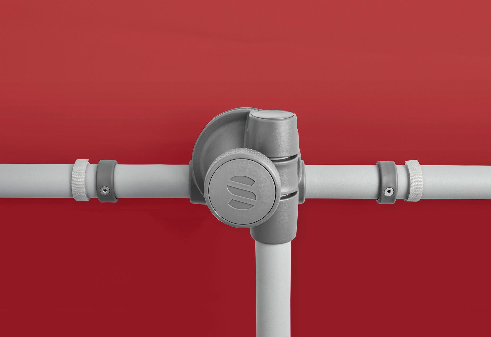 Nahaufnahme eines grauen Sonnenschirm-Gelenks vor rotem Hintergrund, seitliche Perspektive