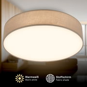 Runde, flache Deckenleuchte mit beigem Stoffschirm und warmweiß leuchtender, diffuser Abdeckung, Nahaufnahme aus leicht schräger Untersicht im Wohnraum
