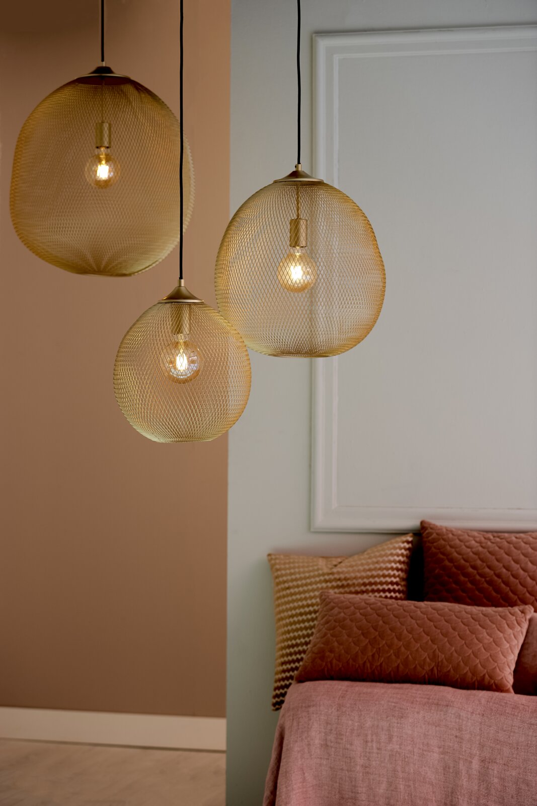 Drei moderne Hängeleuchten mit goldenen, netzartigen Schirmen, die von der Decke hängen. Perspektive von der Seite.