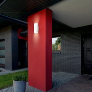 Moderne Akku-Außenwandleuchte an einer roten Wand, seitliche Perspektive