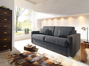 Graues Verwandlungssofa in modernem Wohnzimmer, seitliche Perspektive, mit hellem Tageslicht und stilvoller Dekoration.