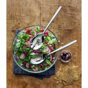 Vogelperspektive auf ein Salat-Set Taverno mit einer Glasschüssel voller frischem Salat, zwei glänzenden Salatbestecken und einer kleinen Schale mit Oliven auf einem Holztisch.