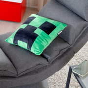 Groen-zwart Minecraft Creeper-kussen op een grijze bank, schuin van bovenaf gefotografeerd (bovenaanzicht/diagonaal perspectief)