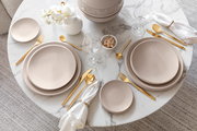 Elegante Tischdekoration mit Speisetellern NewMoon 27cm, goldfarbenem Besteck und weißen Servietten auf einem runden Marmortisch, Vogelperspektive.