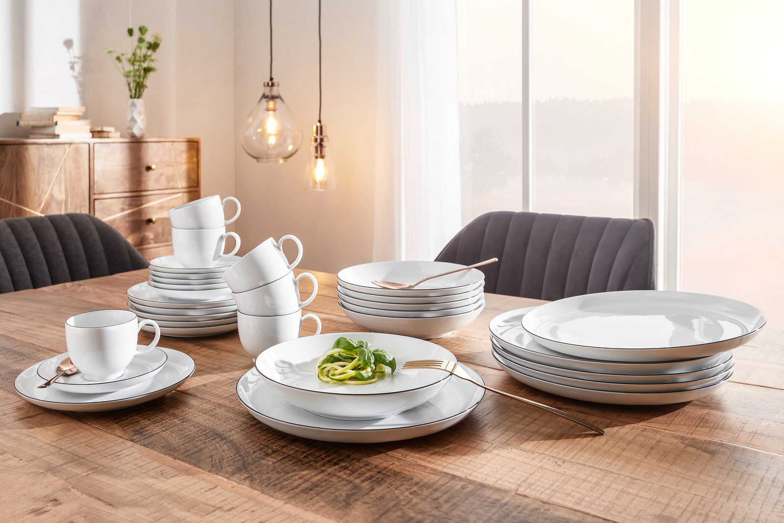 Elegantes Kombiservice Lido Black 30-teilig auf einem Holztisch, mit Tellern, Tassen und Schalen in einem modernen Esszimmer, seitliche Perspektive.