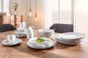 Elegantes Kombiservice Lido Black 30-teilig auf einem Holztisch, mit Tellern, Tassen und Schalen in einem modernen Esszimmer, seitliche Perspektive.