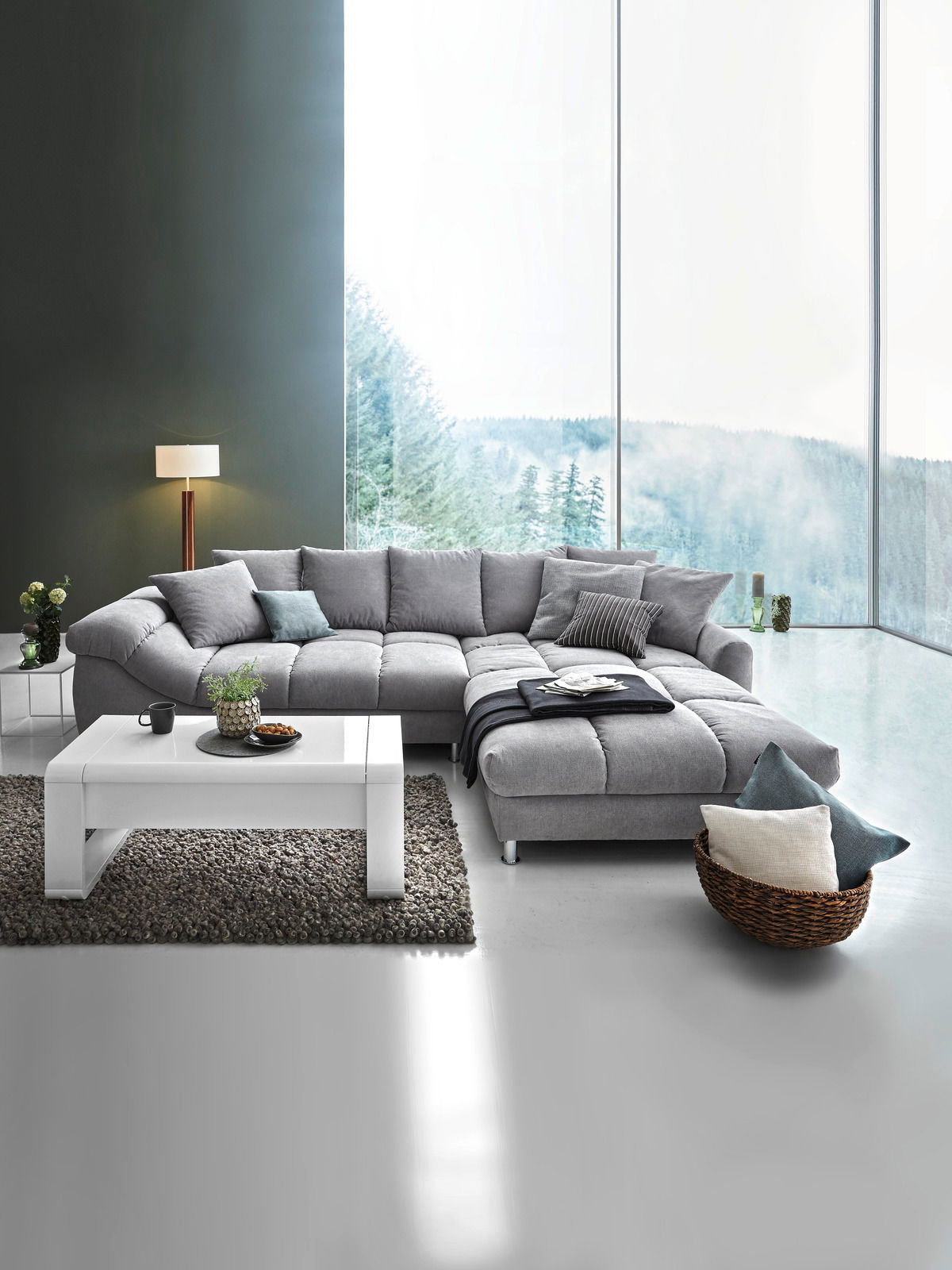 Graue Rundecke (L) in modernem Wohnzimmer mit großem Fenster, Blick von vorne.