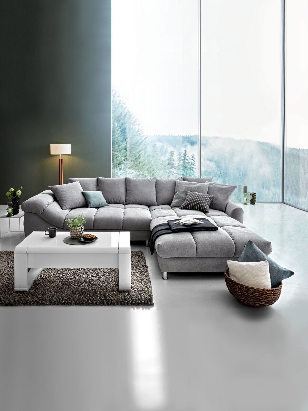 Graue Rundecke (L) in modernem Wohnzimmer mit großem Fenster, Blick von vorne.