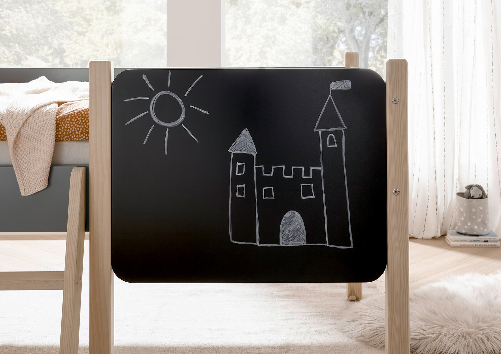 Seitenansicht eines Hausbetts mit einer Tafel, auf der eine Burg und eine Sonne gezeichnet sind.