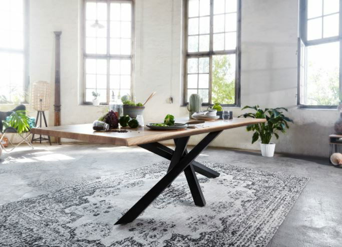 Moderner Esstisch aus Holz mit schwarzem Metallgestell in einem hellen Raum, seitliche Perspektive