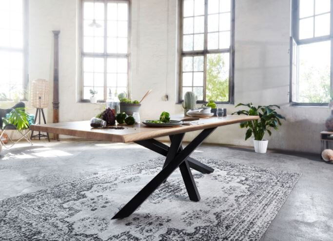 Moderner Esstisch aus Holz mit schwarzem Metallgestell in einem hellen Raum, seitliche Perspektive