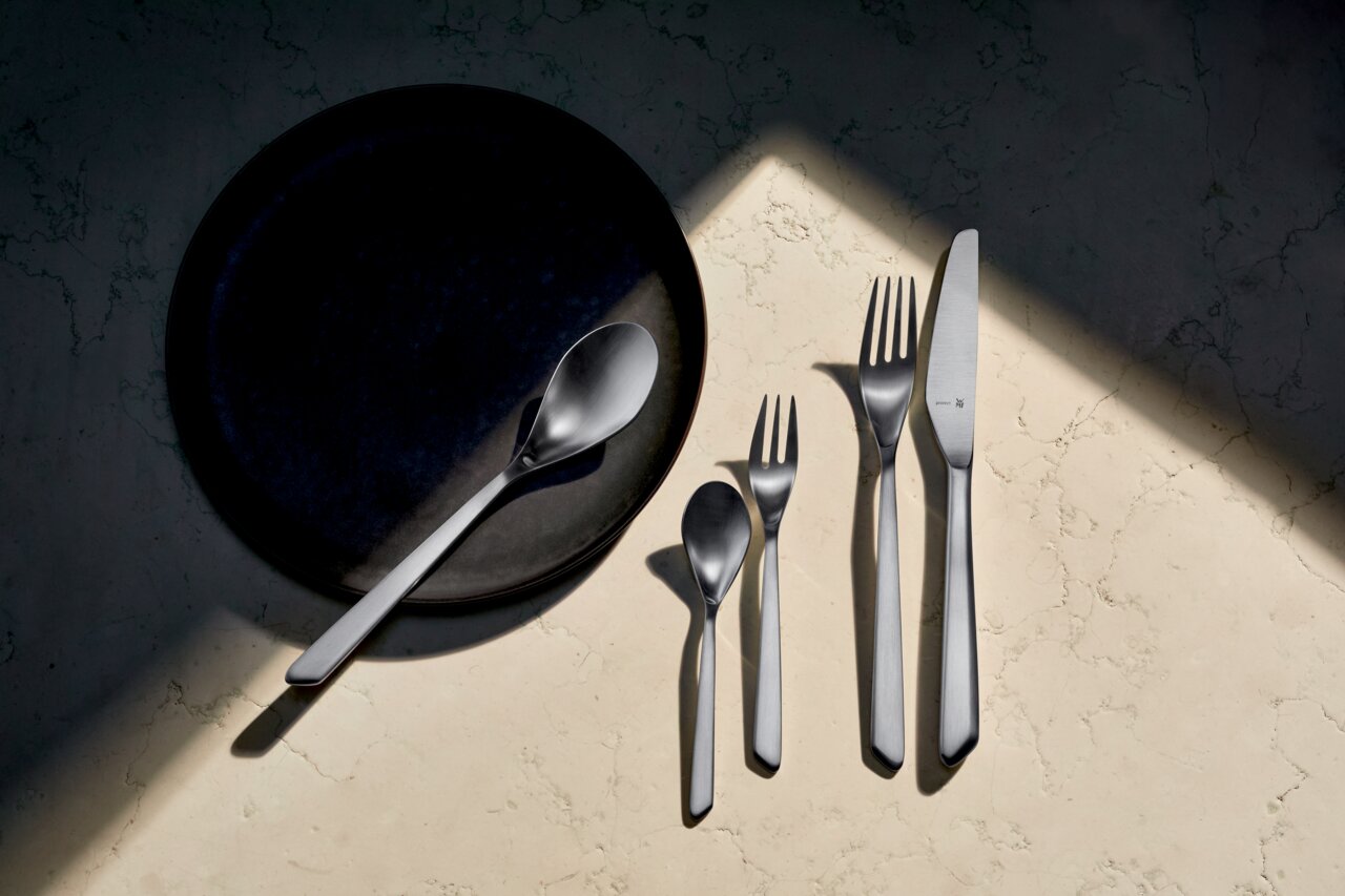 Besteckset Neo 30-tlg. aus Edelstahl, bestehend aus Messer, Gabel, Löffel und Teelöffel, auf einem hellen Marmortisch von oben fotografiert.
